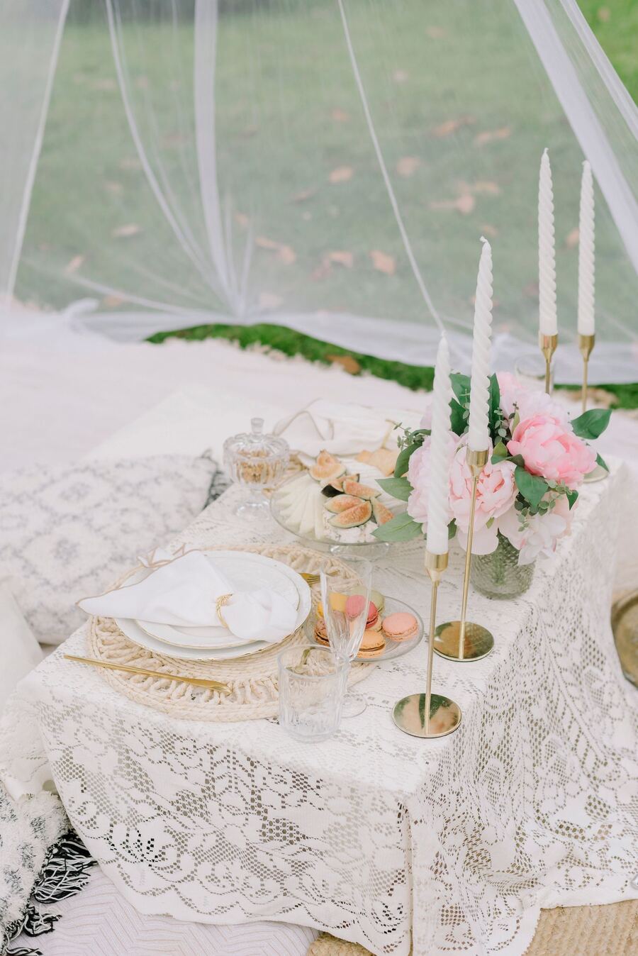 Lace-covered picnic table with peonies, macarons and gold candlesticks