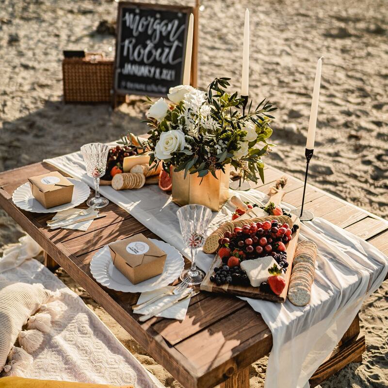Golden hour beach picnic with chalkboard welcome sign
