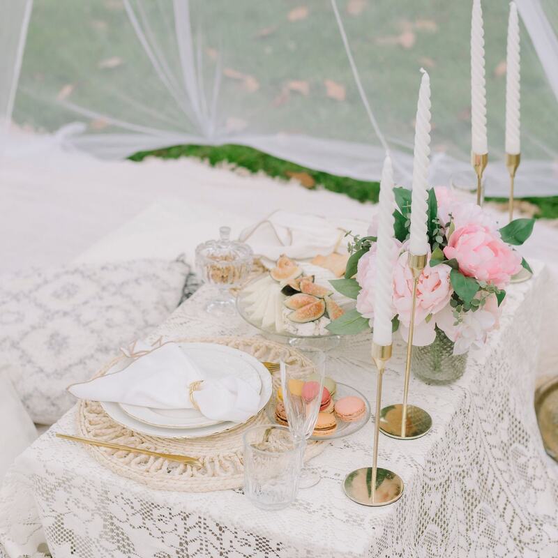 Lace-covered table with pink peonies and taper candles