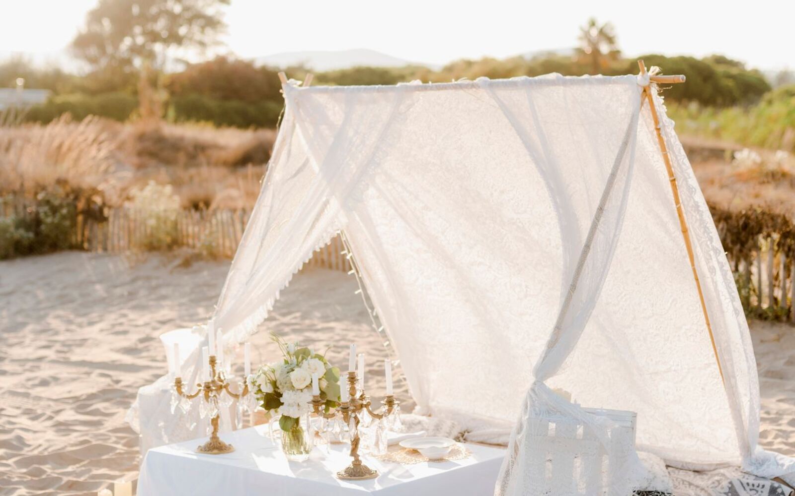Luxury picnic tent styled with candelabras and flowers at golden hour